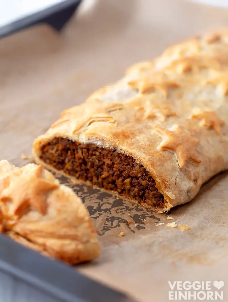 Veganer Braten im Blätterteig mit sternförmiger Dekoration, angeschnitten auf einem Backblech.