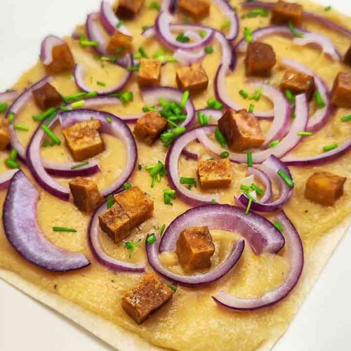 Ein Stück veganer Flammkuchen mit Fertigteig, Cashewmus und Räuchertofu