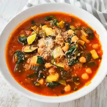 Veganer Gemüseeintopf mit Zucchini, Spinat und Kichererbsen, serviert in einem weißen Teller