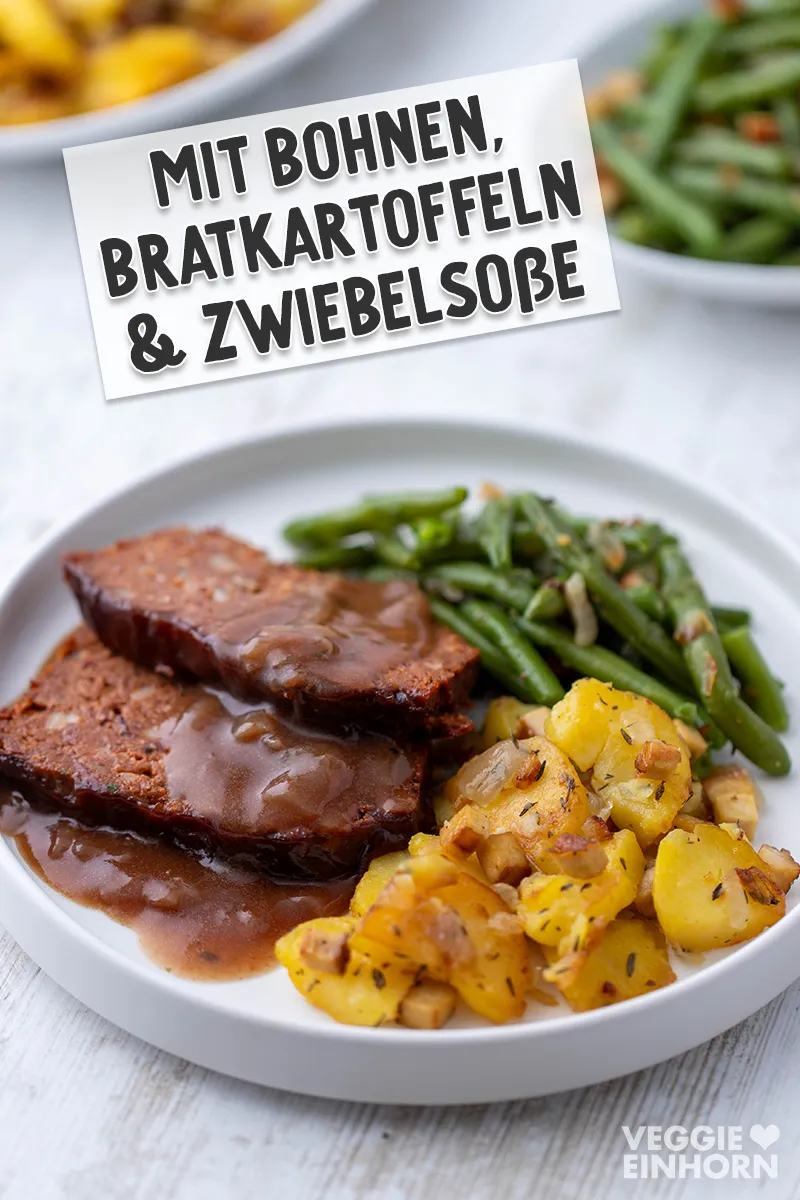 Vegane Scheiben Hackbraten mit brauner Zwiebelsauce, Bratkartoffeln und grünen Bohnen auf einem weißen Teller.