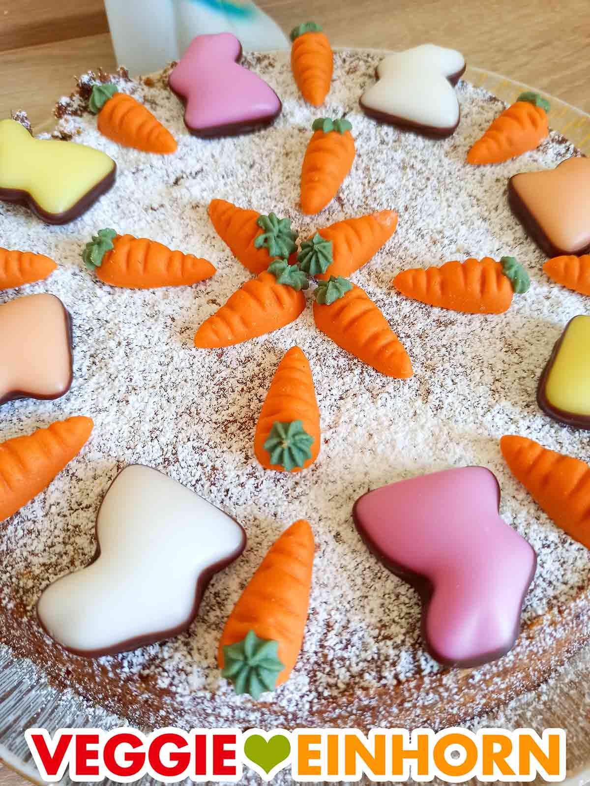 Veganer Rüblikuchen dekoriert mit Puderzucker, Fondant Hasen und Marzipan Karotten
