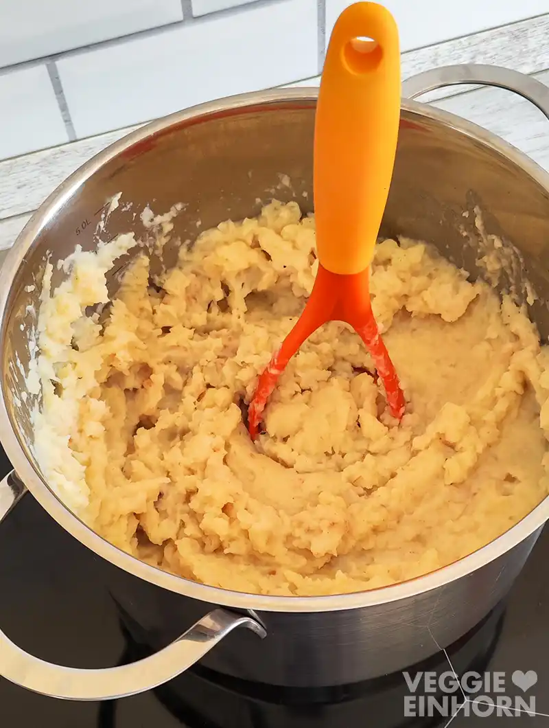 Frisch gestampfter Kartoffel Sellerie Stampf in einem großen Kochtopf mit Kartoffelstampfer.