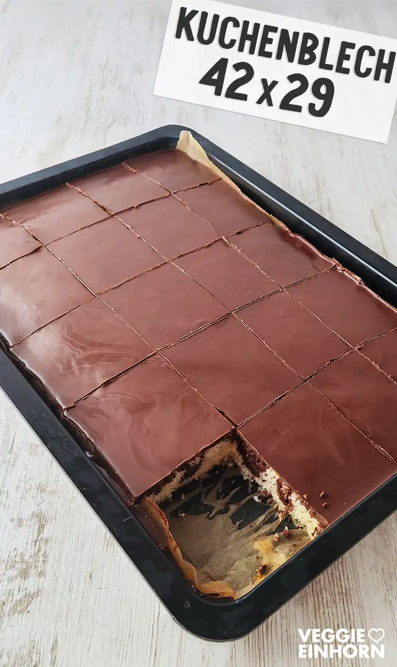 Ein Kuchenblech mit veganem Marmorkuchen mit Schokoglasur, in Stücke geschnitten, ein Stück fehlt bereits.