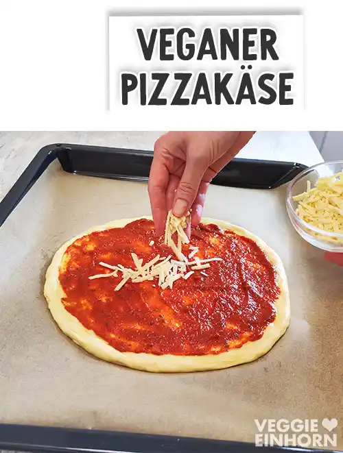 Eine Hand streut veganen Pizzakäse auf einen mit roter Pizzasauce bestrichenen Pizzaboden auf einem Backblech, darüber Textaufschrift Veganer Pizzakäse.