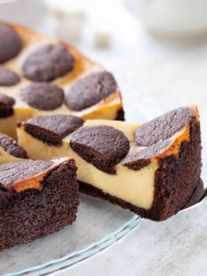 Veganer russischer Zupfkuchen mit cremiger Füllung und schokoladigem Mürbeteig, angeschnitten auf einer Glasplatte.
