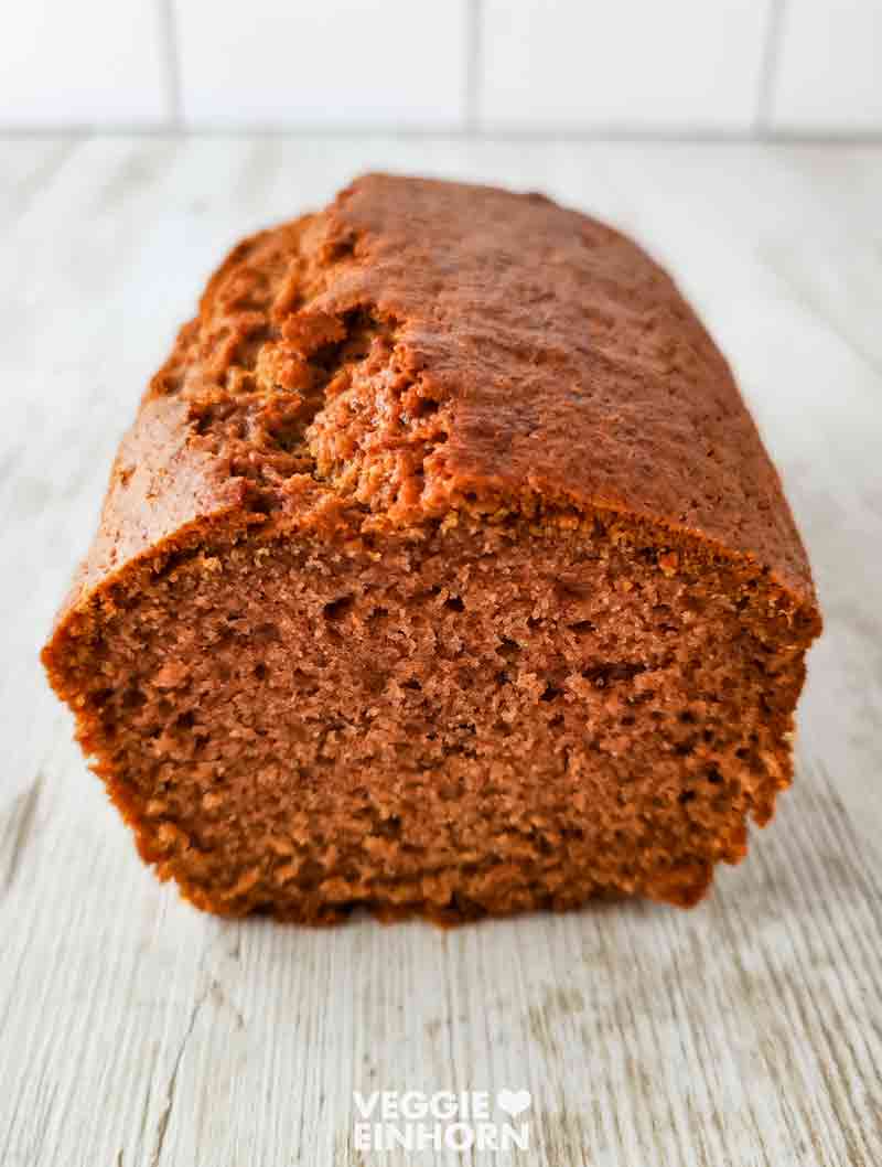 Ein ganzer veganer Kastenkuchen mit Apfelmus auf einem hellen Hintergrund.