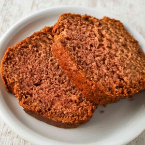 Zwei saftige Scheiben veganer Rührkuchen mit Apfelmus auf einem weißen Teller.