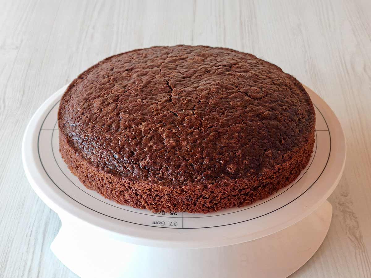 Veganer Schokobiskuit als runder Tortenboden auf einer drehbaren Tortenplatte.