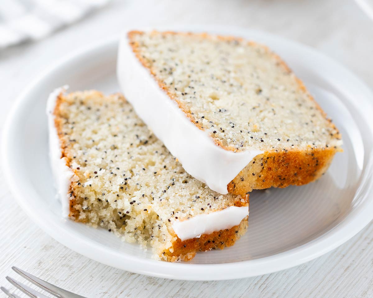 Zwei Stücke veganer Mohn Zitronen Kuchen auf einem Kuchenteller.