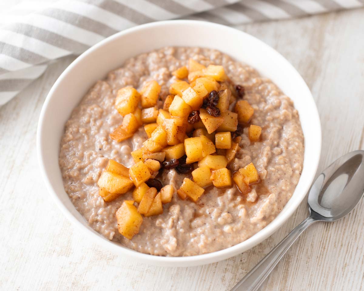 Veganer Apfel-Zimt-Porridge mit Apfelstücken in einer weißen Schüssel.