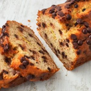 Saftiges veganes Bananenbrot mit Zartbitter-Schokotropfen, einige Scheiben sind abgeschnitten.