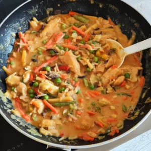 Veganes Hähnchen Curry mit cremiger Erdnussbutter-Kokosmilch-Soße mit buntem Wok-Gemüse in einer schwarzen Pfanne.