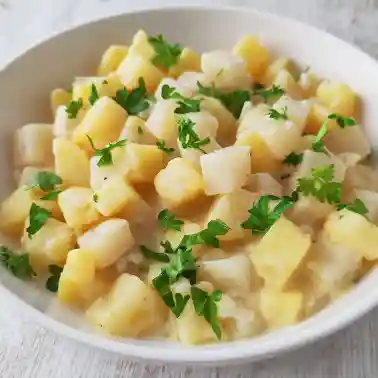Veganes Kohlrabi-Kartoffel-Gemüse mit cremiger Soße und frischer Petersilie serviert auf einem weißen Teller.