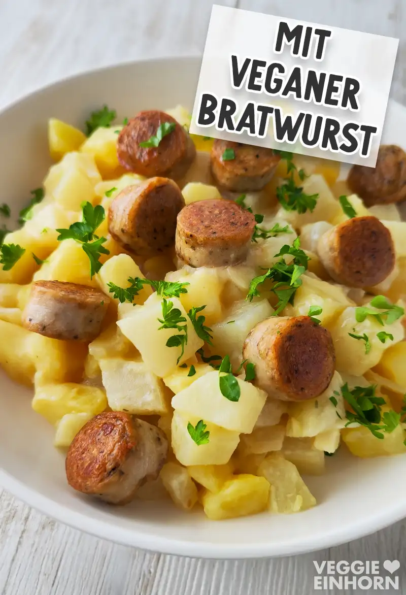 Ein Teller veganes Kohlrabi-Kartoffel-Gemüse mit geschnittener veganer Bratwurst und Petersilie.