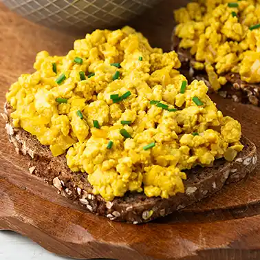 Veganes Tofu Rührei auf einer Scheibe Brot, garniert mit Schnittlauch.