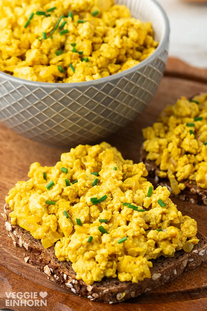 Nahaufnahme von einem Brot mit veganem Tofu Rührei, bestreut mit Schnittlauchröllchen.