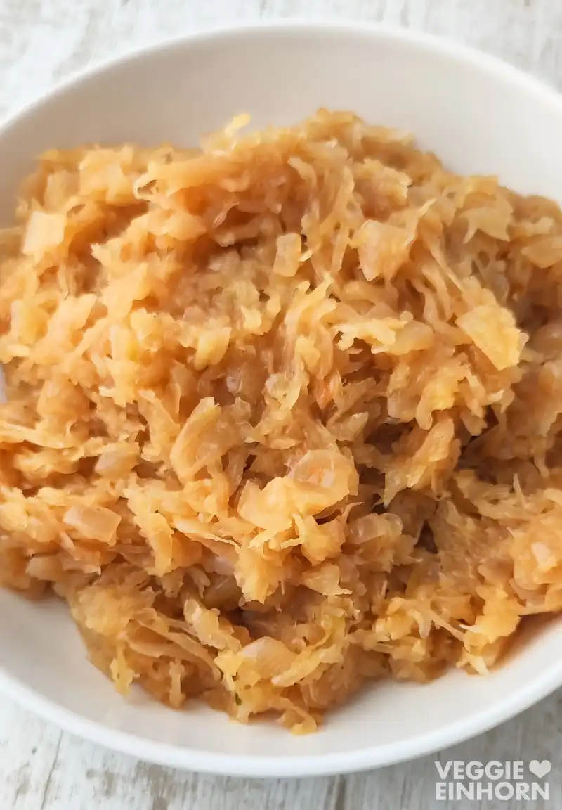 Veganes Sauerkraut Nahaufnahme von gekochtem veganem Sauerkraut in einer weißen Schüssel.