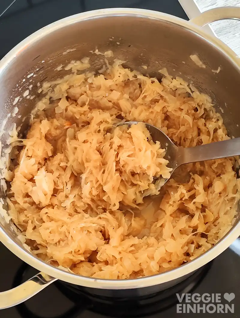 Frisch gekochtes veganes Sauerkraut in einem Topf mit einem Löffel.