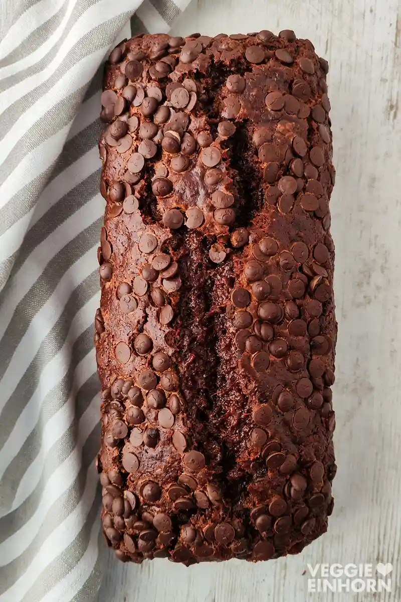 Ein veganes Schoko-Bananenbrot ist von oben fotografiert, die Oberfläche ist dicht mit Schokotropfen bedeckt.