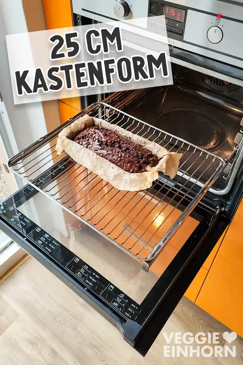 Ein frisch gebackenes veganes Schoko-Bananenbrot steht in einer mit Backpapier ausgelegten 25-cm-Kastenform auf einem Backofenrost im geöffneten Ofen.