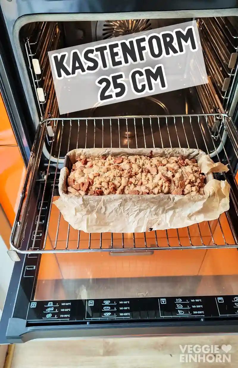 Ein fertig gebackenes veganes Spekulatius Bananenbrot in einer mit Backpapier ausgelegten 25 cm Kastenform steht im geöffneten Backofen.