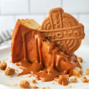 Veganes Weihnachtsdessert bestehend aus Käsekuchen mit Lotus Biscoff Creme und Spekulatius auf einem weißem Teller.