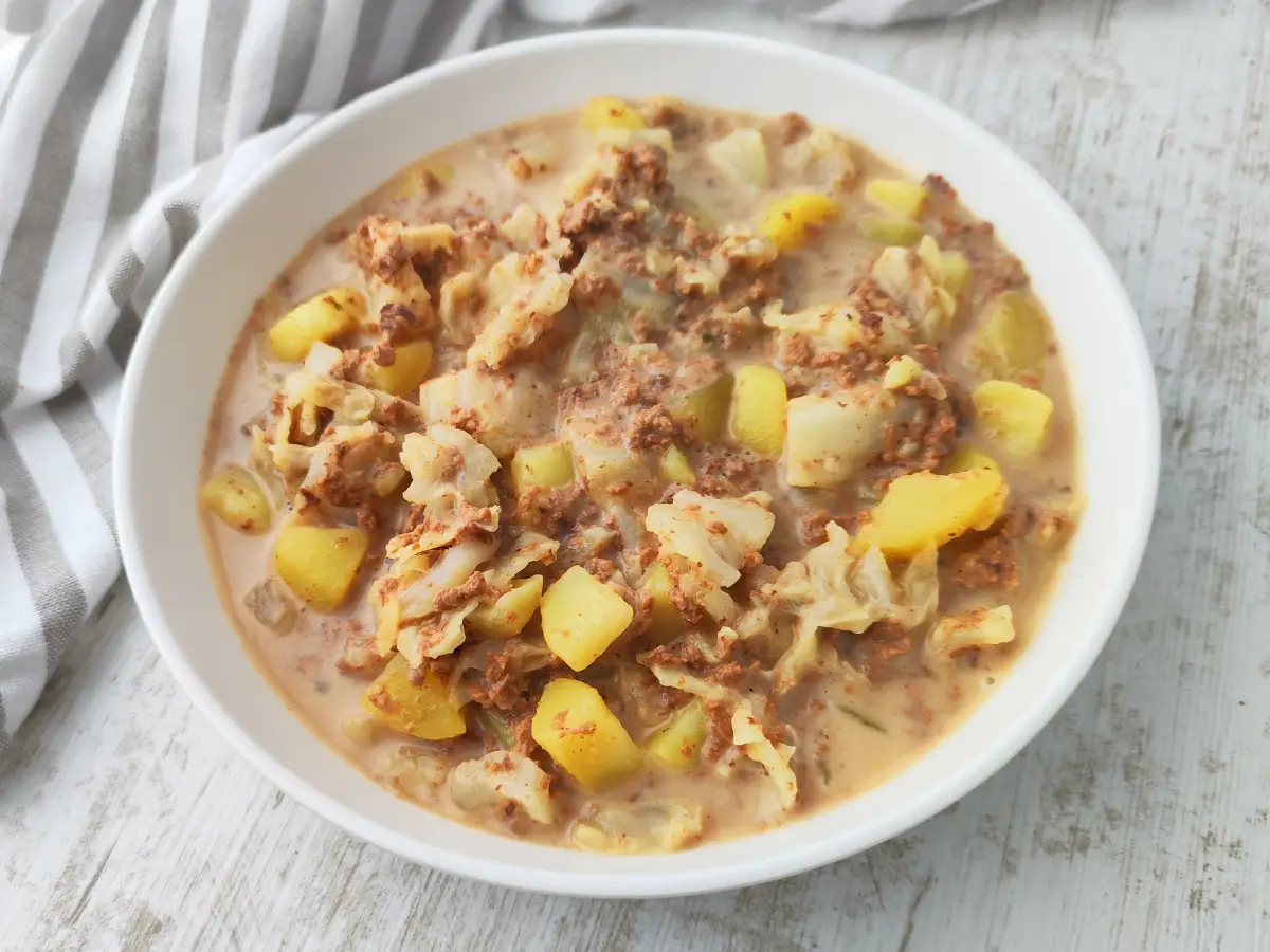 Veganer Wirsingeintopf mit veganem Hack und Kartoffeln auf einem weißen Teller.