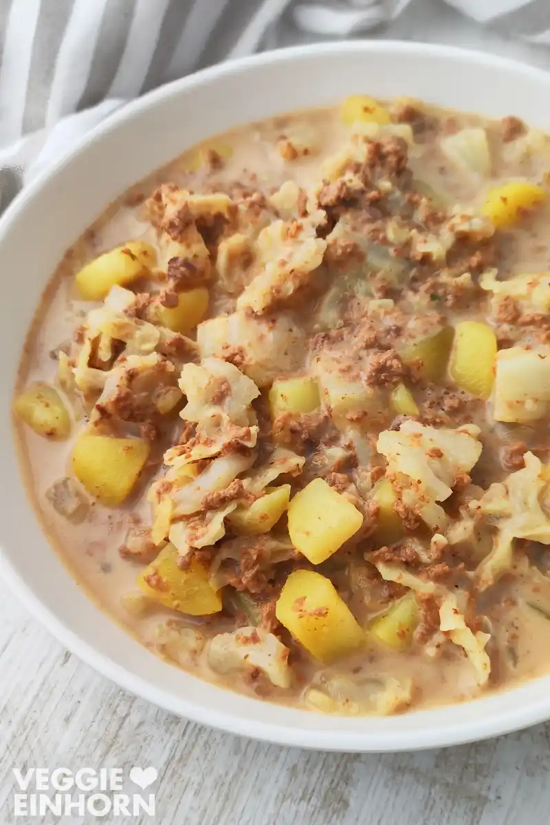 Teller mit veganem Wirsingeintopf mit Kartoffeln und veganem Hackfleisch.