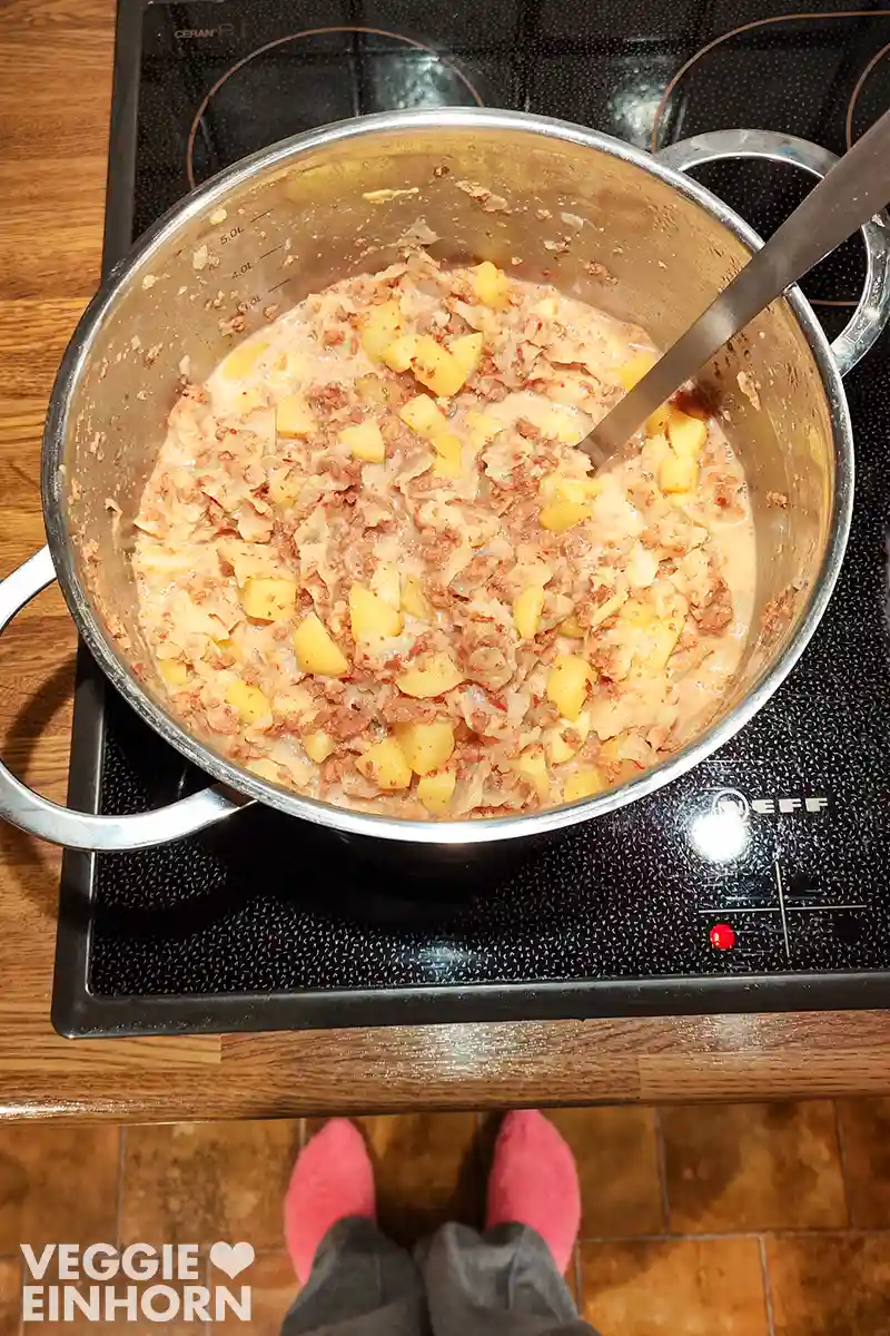 Ein großer Topf mit veganem Wirsingeintopf steht auf einem Herd.