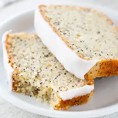 Zwei Stücke veganer Zitronenkuchen mit Mohn, überzogen mit weißer Zitronenglasur.