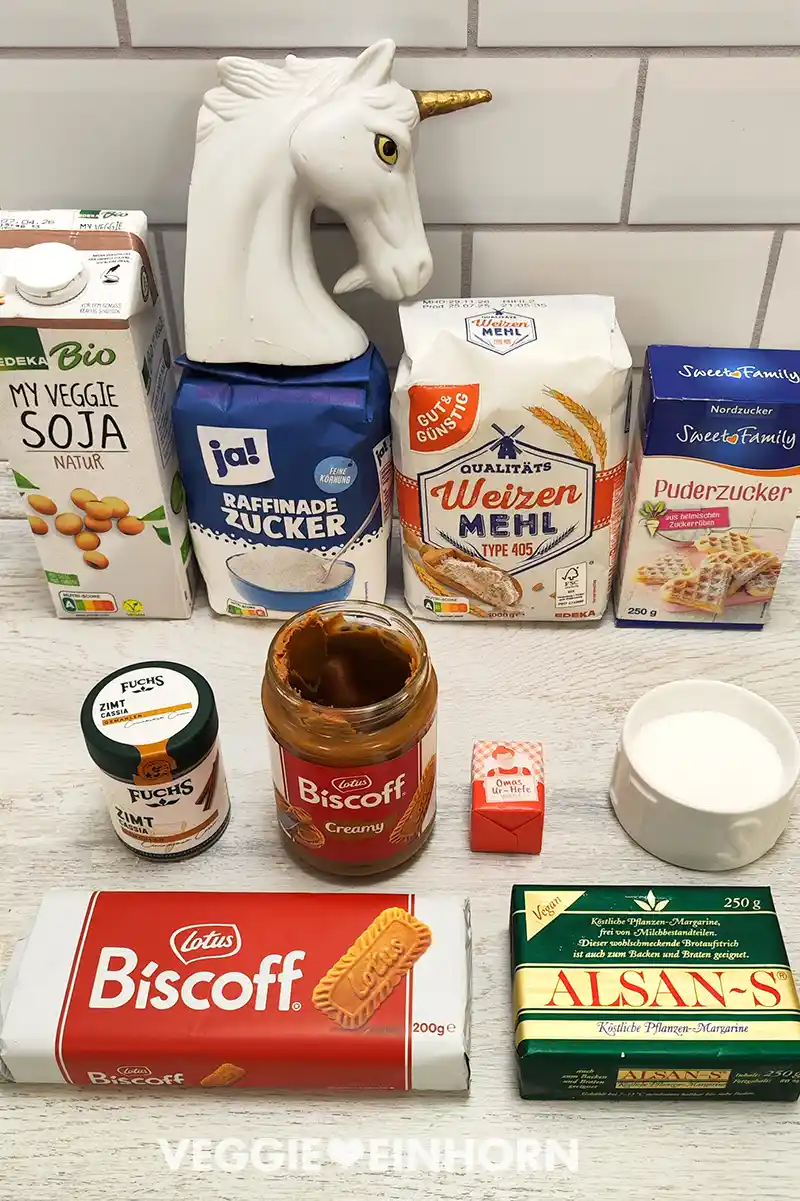 Zutaten für vegane Lotus Biscoff Zimtschnecken, darunter Sojamilch, Zucker, Weizenmehl, Puderzucker, Zimt, Hefe, Lotus Biscoff Creme, Lotus Biscoff Kekse, Salz und vegane Butter.